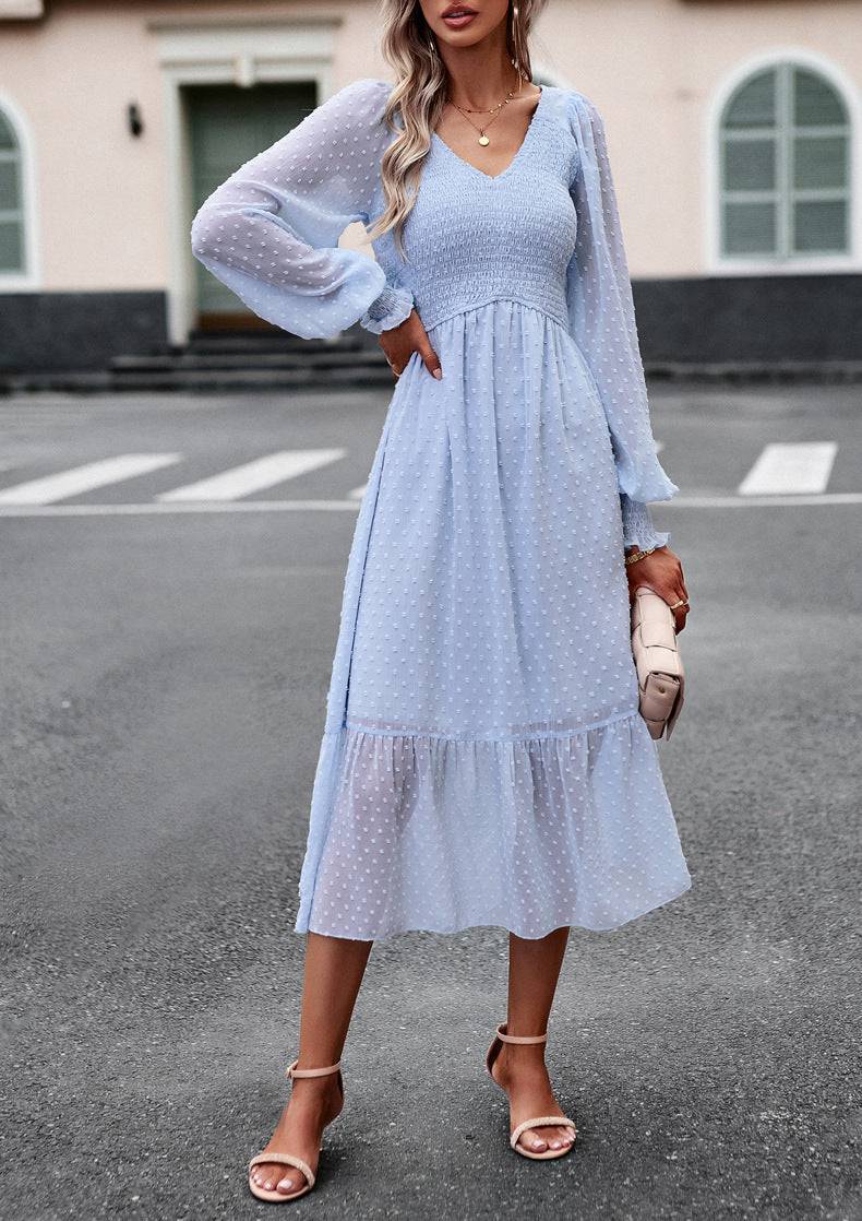 a woman standing in a parking lot wearing a blue dress