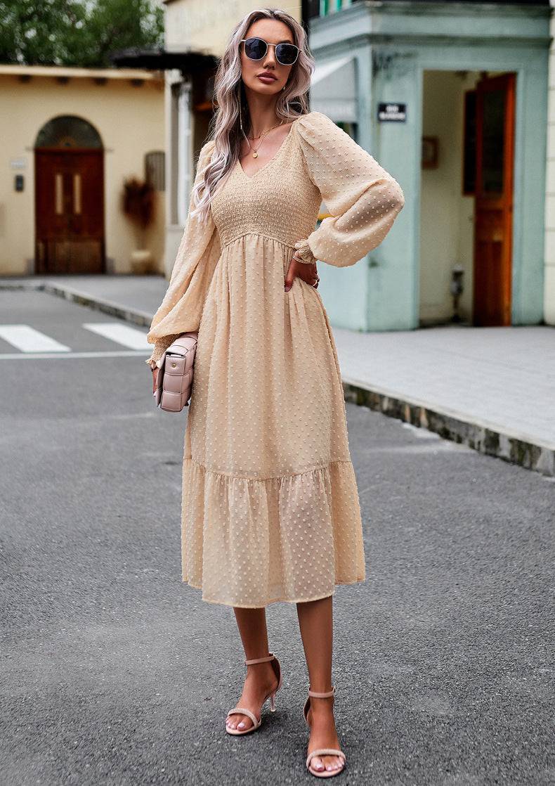 a woman in a beige dress standing on a street