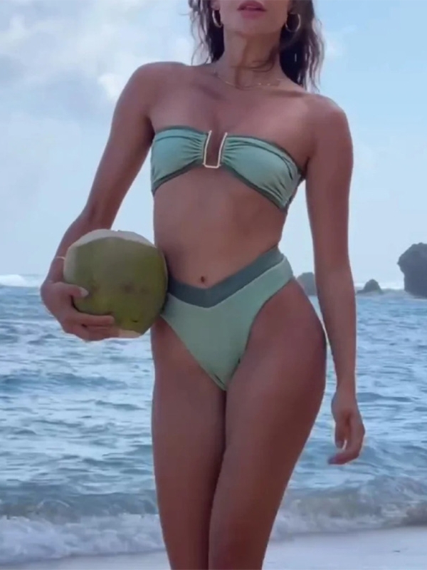 a woman in a green bikini holding a coconut